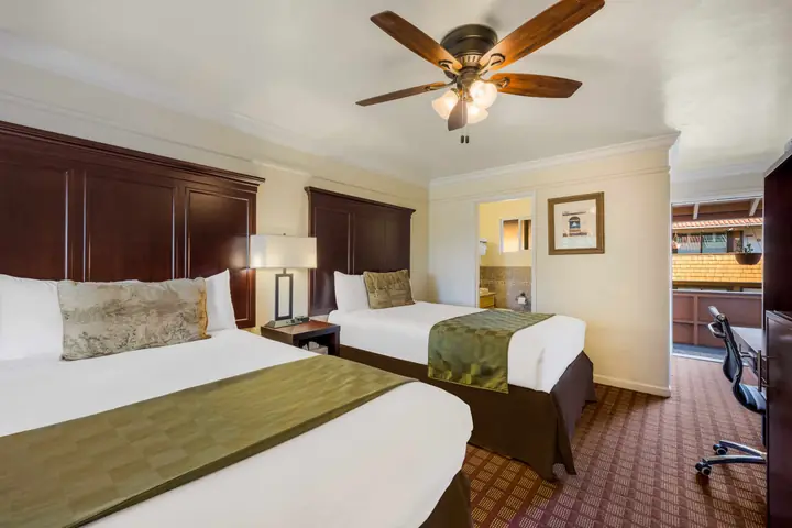 Two queen beds, lamps on a shared nightstand and a doorway through to the bathroom