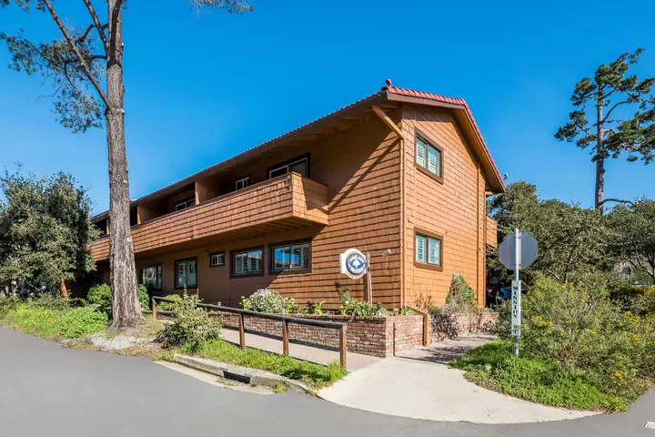 The inn's two-story cedar-shingled building with a long balcony, a red tile roof and a small Clarion Collection sign by the street corner
