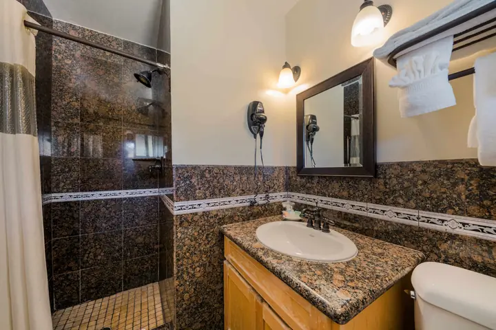 Bathroom with a granite-tiled shower, a granite vanity and a hair dryer on the wall